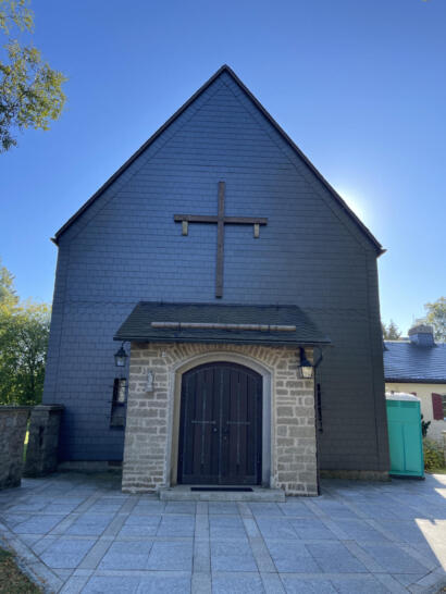Fornatlansicht der katholischen Kirche im Sommer mit Vorbau und Eingangstür.